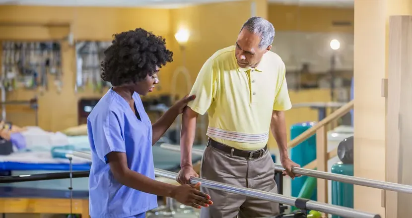 Physical therapist assistant helping patient regain balance while walking